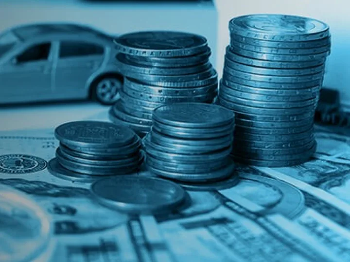 Stacked coins and a model car resting on banknotes