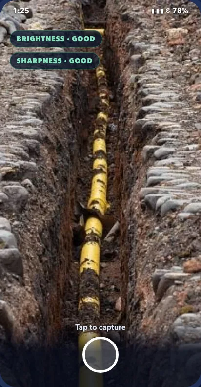 Phone camera pointed into an open trench with a yellow gas pipe, quality checks reading Brightness good and Sharpness good